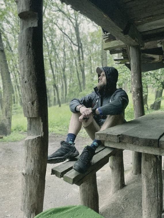 Samuel sedí pod dreveným prístreškom v lese